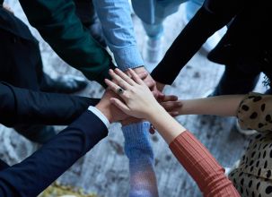 Picture of peoples hands joining together in the middle of the picture