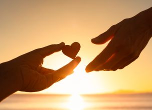 Picture of two hands with a small heart being passed between them